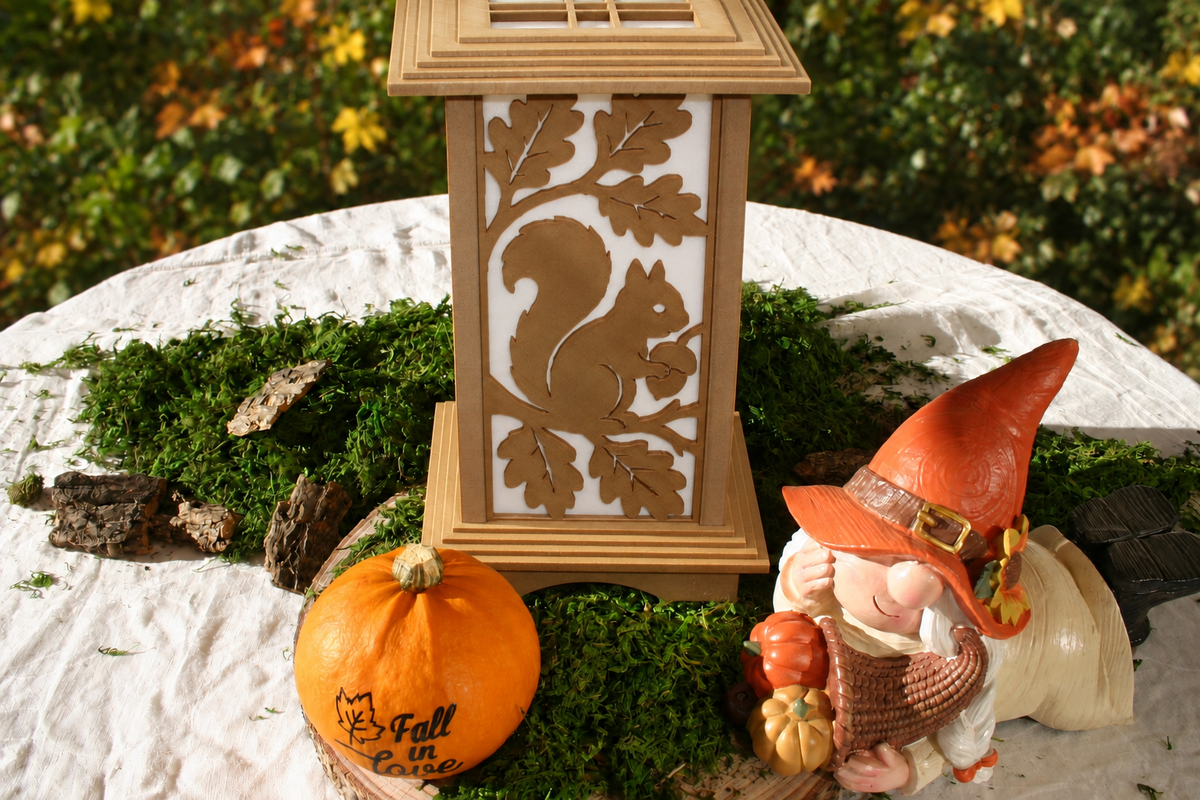 Kyoto lamp with Squirrel & Acorn panel displayed among moss, a pumpkin and a gnome